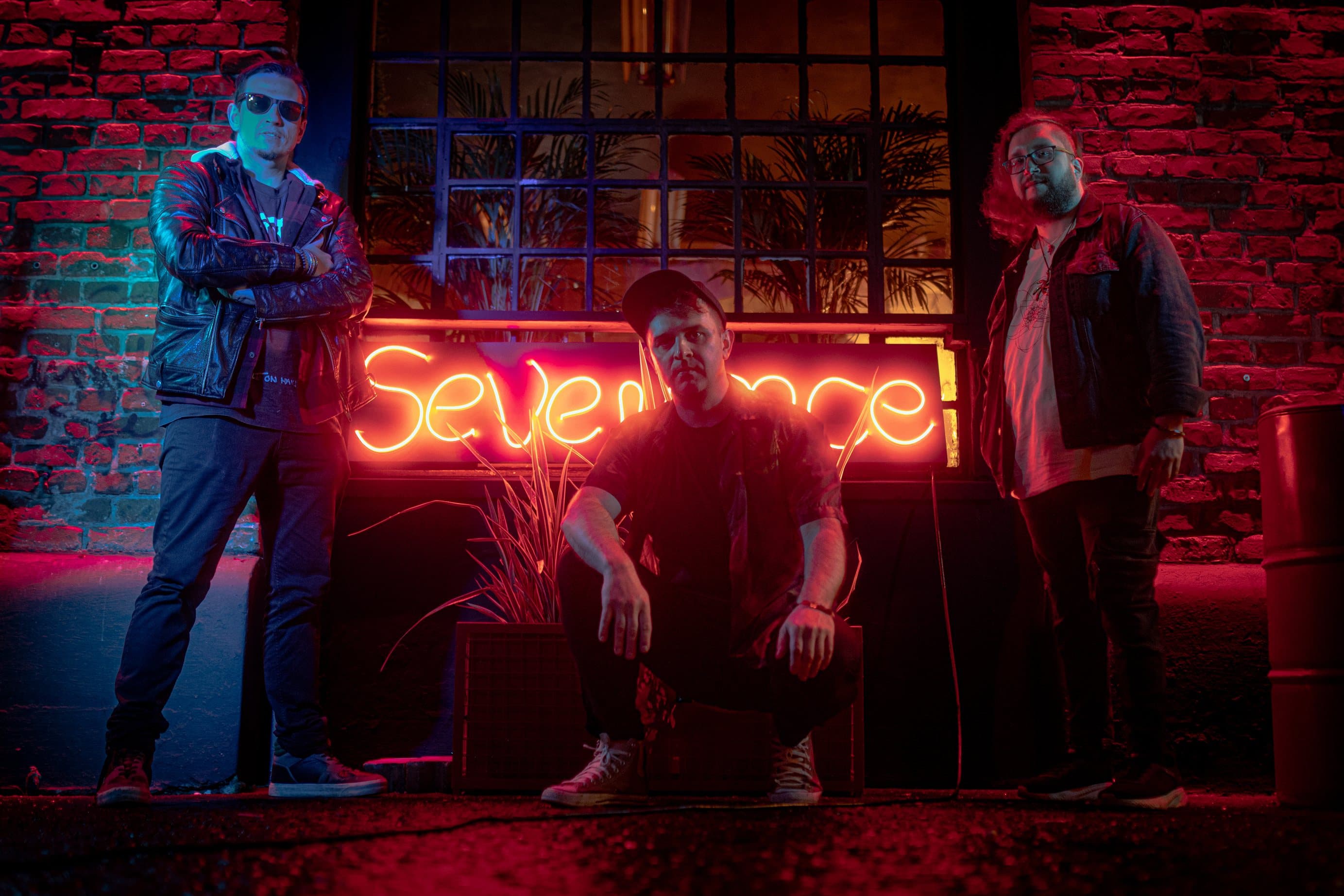 SEVENANCE band standing with neon sign