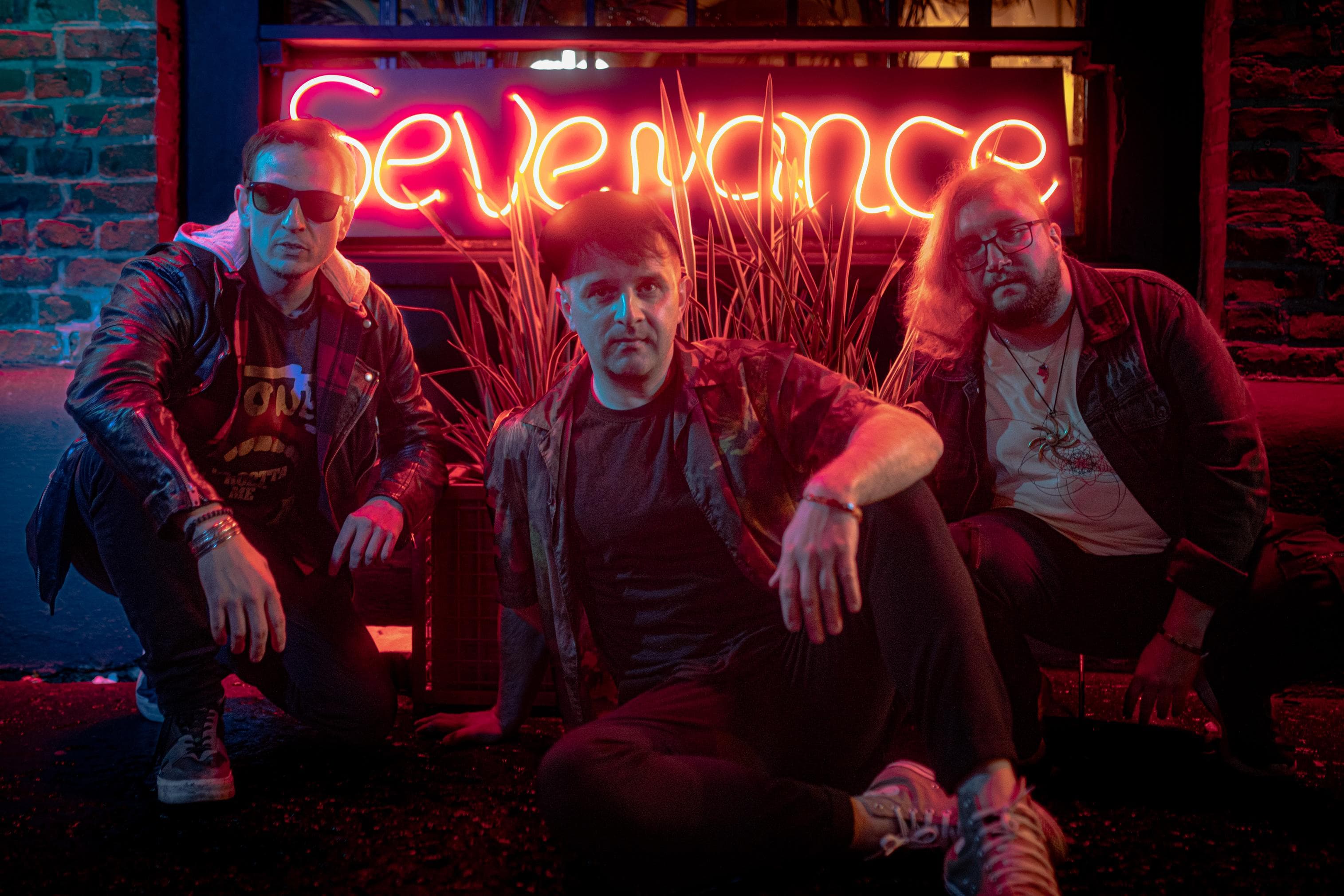 SEVENANCE band crouching with neon sign